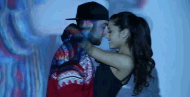 a man and a woman are hugging and kissing in front of a wall .