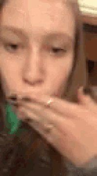 a woman is covering her mouth with her hand while eating a sandwich .