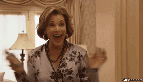 a woman in a floral shirt and necklace is holding a remote control in her hand while smiling ..