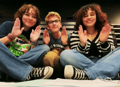 a boy wearing a shirt that says underneath is sitting with two girls