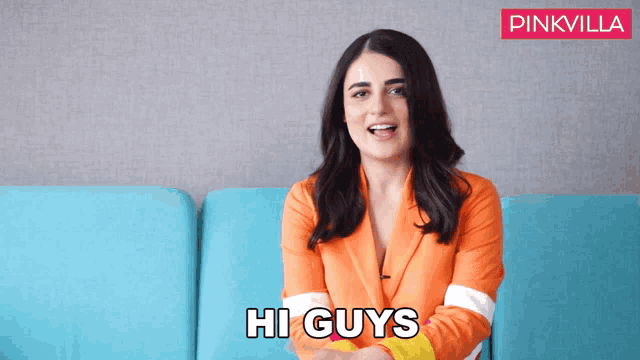 a woman sitting on a blue couch with the words hi guys behind her