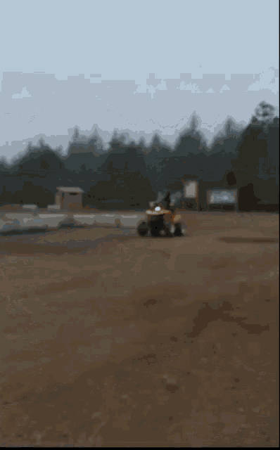 a person is riding a lawn mower in a dirt field
