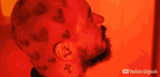 a man with hearts on his head has a tattoo of a cross on his neck