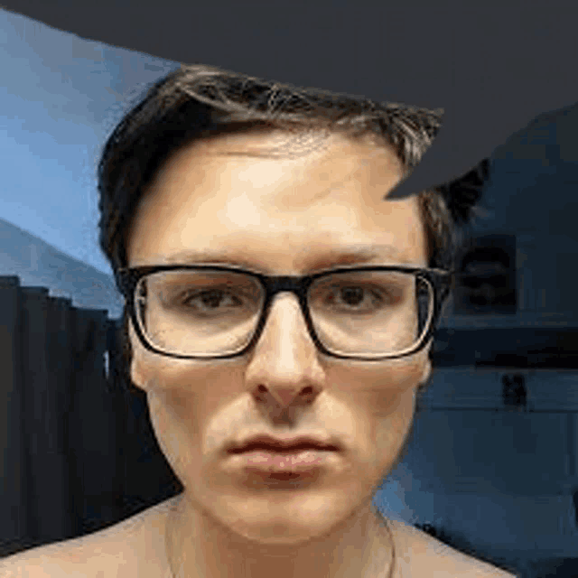 a close up of a man wearing glasses and a shirtless face .