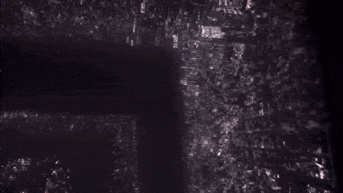 an aerial view of a city at night with a shadow on the ground