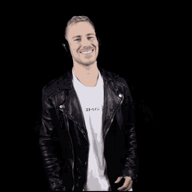 a man wearing headphones and a leather jacket smiles for the camera