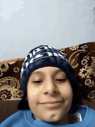 a young boy wearing a blue sweater and a blue hat