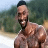a shirtless man with a beard is smiling while standing on a beach .
