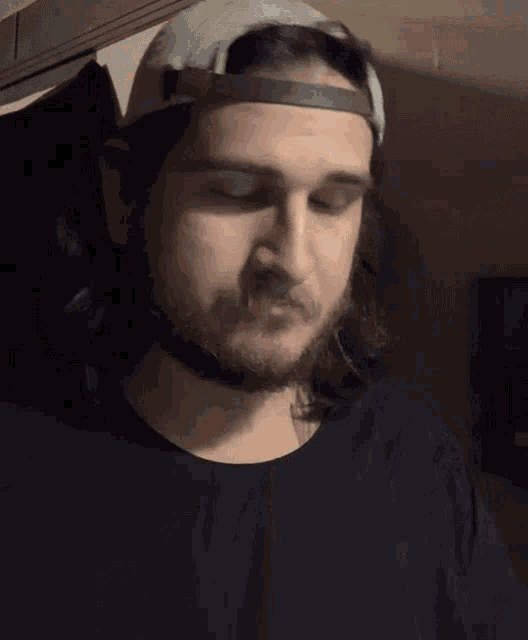a man with long hair wearing a baseball cap