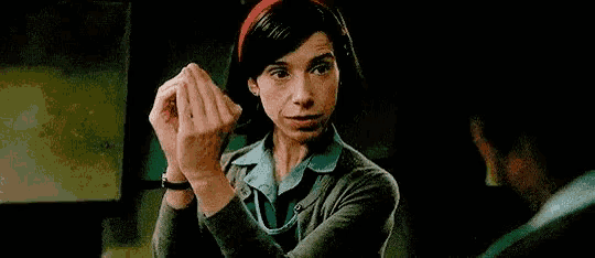 a woman is pointing at a man with her finger while making a funny face .