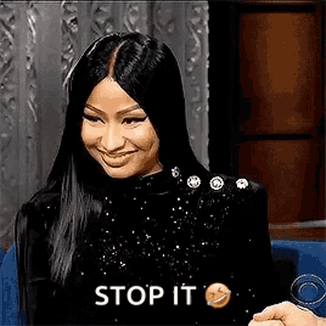 a woman with long black hair is sitting in a chair and smiling with the words `` stop it '' .