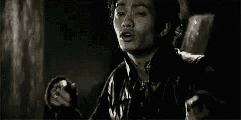 a man in a black leather jacket is standing in a dark room .