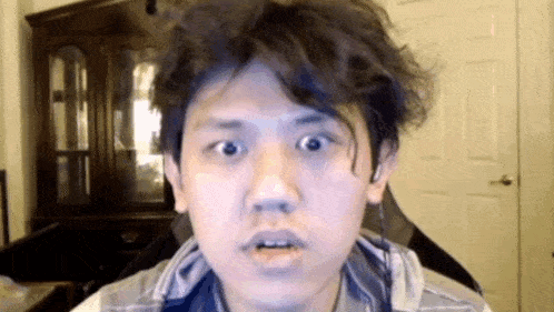 a young man with a messy haircut is making a funny face while looking at the camera .