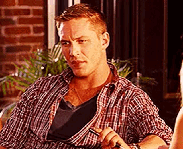 a man in a plaid shirt is sitting at a table holding a pen in his hand .