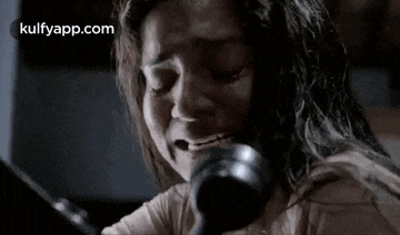 a woman is crying while talking on a phone in a dark room .