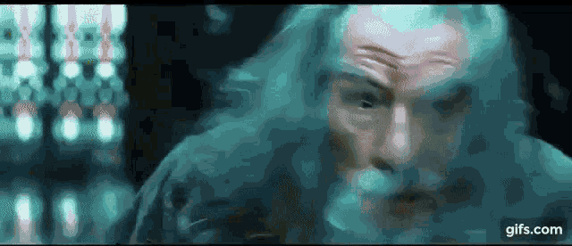 a man with long hair and a beard is standing in front of a blurred background .