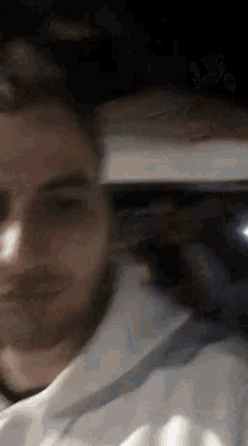 a close up of a man 's face with a beard and a white shirt .