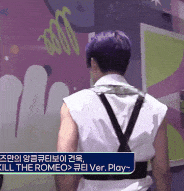 a man with purple hair is standing in front of a sign that says kill the romeo ver play