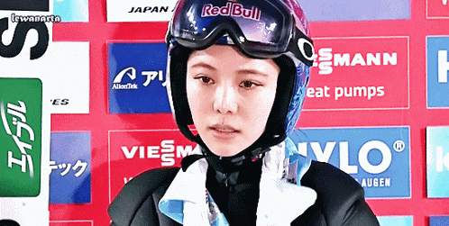 a woman wearing a helmet and goggles with red bull on it