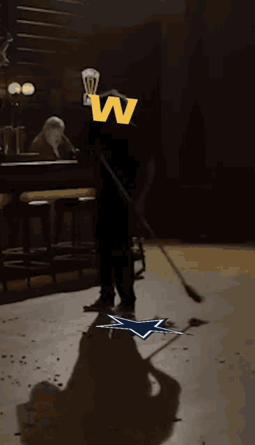 a man is sweeping the floor in a dark room with a w on his head
