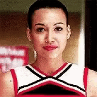 a cheerleader is wearing a red , white and black uniform and smiling .