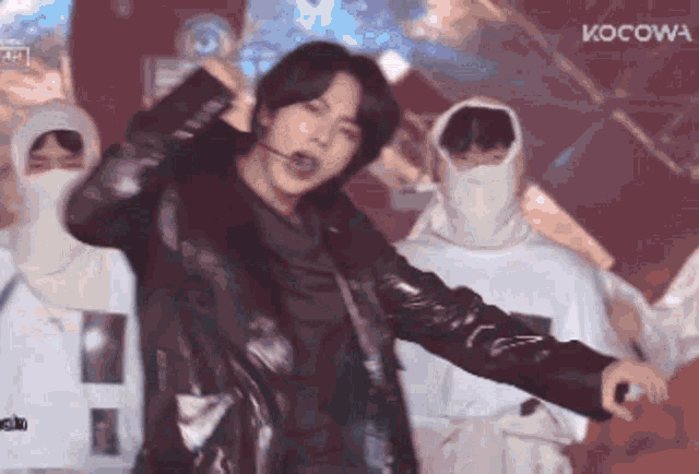 a man in a black jacket is dancing on a stage with kocow written on the bottom