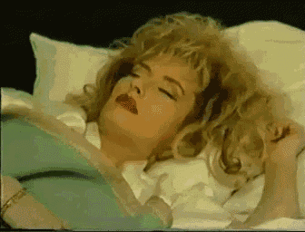 a woman is laying on a bed with her eyes closed and her mouth open .