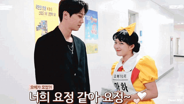 a man and a woman are standing next to each other in a hallway with a sign that says kbg on it