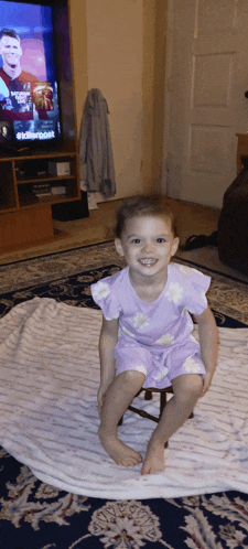 a little girl is sitting on a stool in front of a tv screen that says ' fox news ' on it