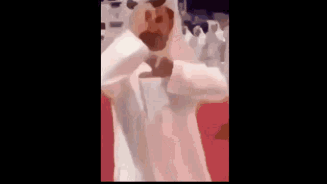 a man with a beard is wearing a white robe and sunglasses and making a funny face .