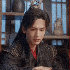 a man in a costume is sitting at a table in front of a window .