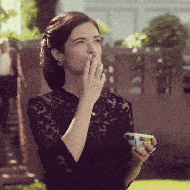 a woman in a black lace top is holding a cup of coffee