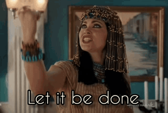 a woman in a cleopatra costume holds up her fist and says " let it be done "