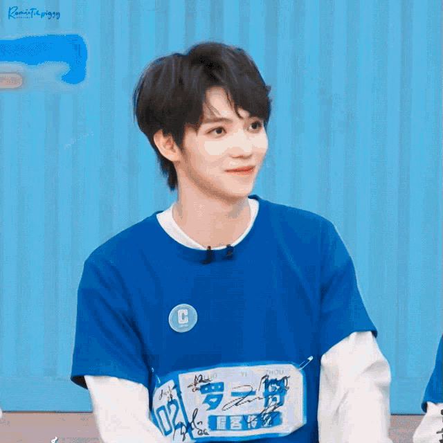 a young man wearing a blue shirt with the letter c on the front