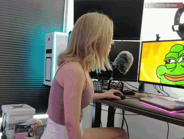a woman sitting in front of a computer monitor with a watermark that says ' ainity.divine '