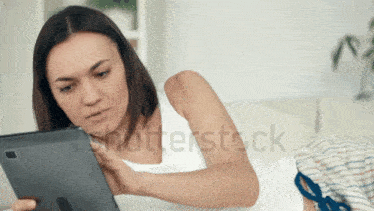 a woman laying on a couch looking at a tablet with shutterstock written on the bottom