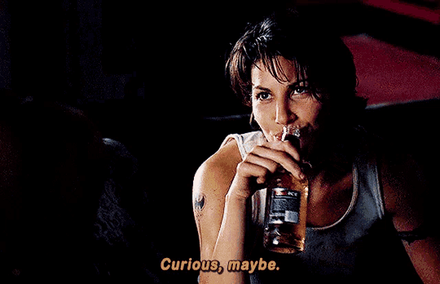 a woman with a tattoo on her arm is holding a bottle of whiskey and says " curious maybe "