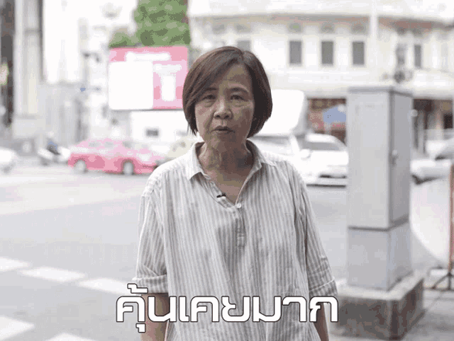 a woman in a striped shirt stands in front of a sign that says ' ui '
