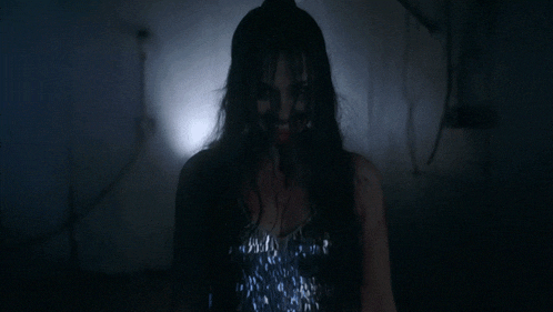 a woman with a bloody face is wearing a silver top