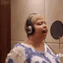 a woman is singing into a microphone while wearing headphones .