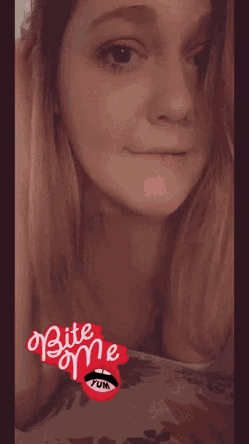 a woman smiles with a bite me fun sticker on her lips