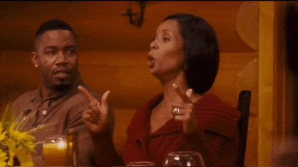 a man and a woman are sitting at a table talking to each other .
