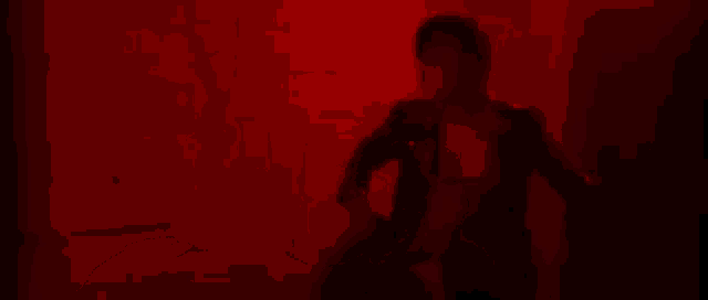 a man is running in a dark room with a red light on the wall .