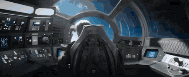 a man is sitting in the cockpit of a space ship with a steering wheel that says ' x ' on it
