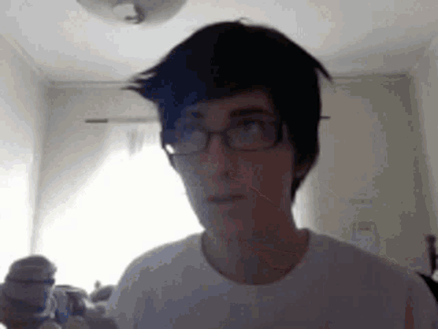 a person wearing glasses and a white shirt is looking at the camera