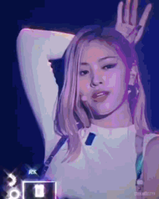 a woman with blonde hair is making a peace sign with her hand while standing in front of a microphone .