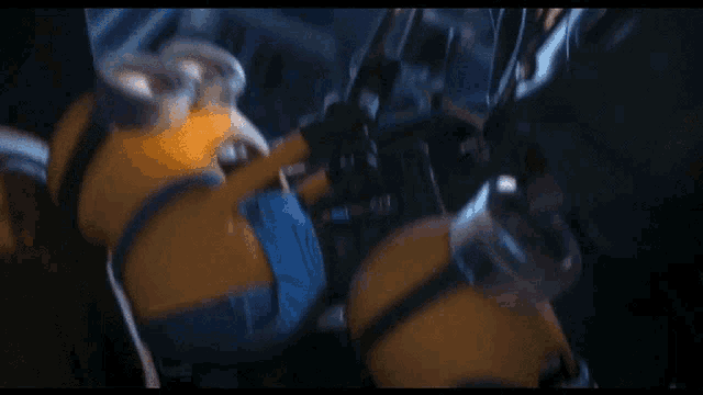 a close up of a yellow minion with a blue shirt and goggles