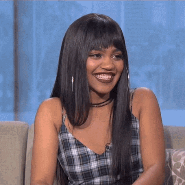 a woman with long hair is sitting on a couch and smiling