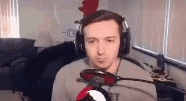 a man wearing headphones and a rooster hat is sitting in front of a microphone .