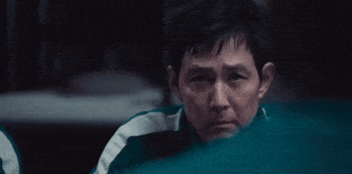 a man in a green and white jacket is looking at the camera .